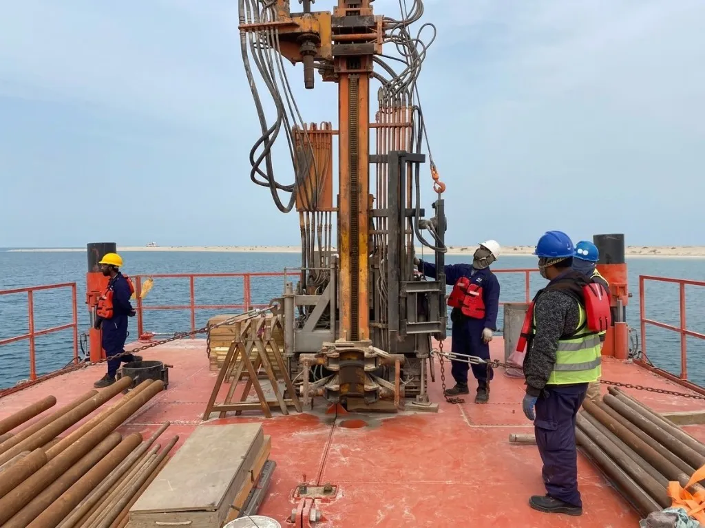 Workers beside a drilling rig on a barge
