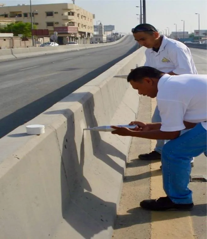 Workers examining a concrete barrier