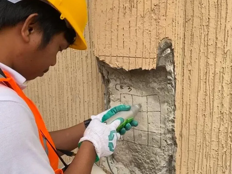 Worker inspecting a building wall with a handheld device